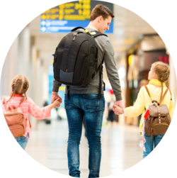 A man holding hands with two young girls, walking together in an airport terminal.